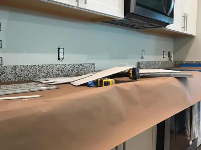 Granite countertop and tile backsplash with cabinets protected during installation