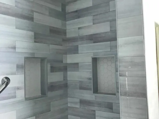 Walk-in shower with gray wood-look wall tile, recessed niche and grab bar