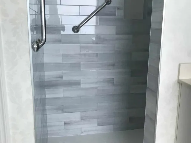 Close view of a tiled shower wall with two recessed niches and a grab bar