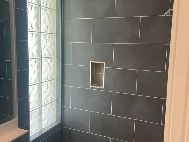 Dark large-format tile shower walls with a niche during installation