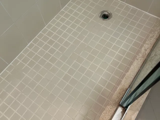 Mosaic shower floor with bright white grout after cleaning and color sealing