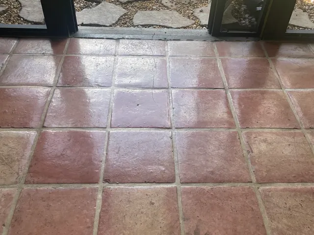 Faded Saltillo tile floor with worn finish near a doorway