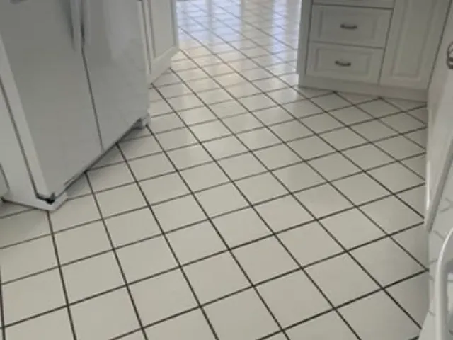 White ceramic kitchen floor with dark, stained grout lines