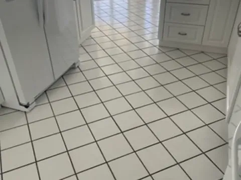 Before: White ceramic kitchen floor with dark stained grout lines before and clean, even light grout after color sealing
