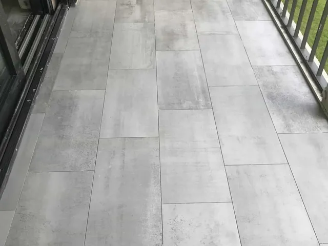 Gray wood-look porcelain plank tile being installed in a room overlooking a pool