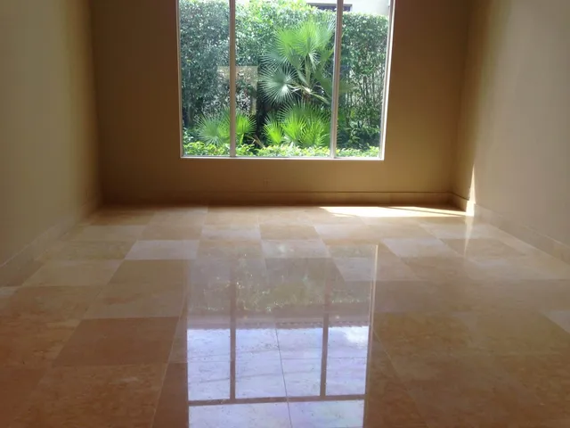 Polished cream marble floor in a Palm Beach County living room with window reflections