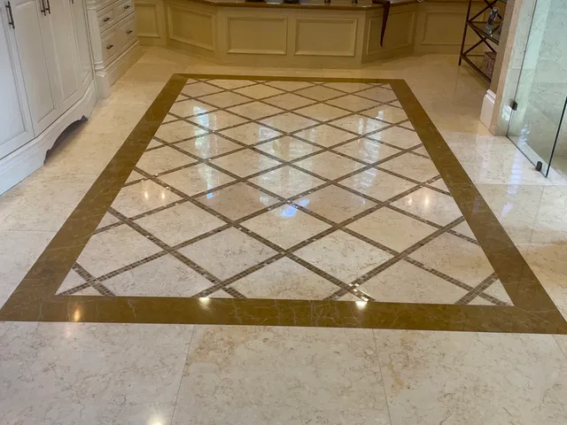 Polished marble entry with a dark diamond-pattern inlay border