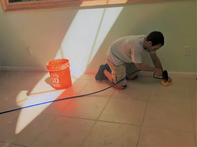 Technician injecting bonding agent into grout joints of a hollow tile floor